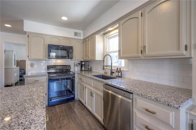 kitchen with sink, dark hardwood / wood-style floors, light stone counters, tasteful backsplash, and black appliances