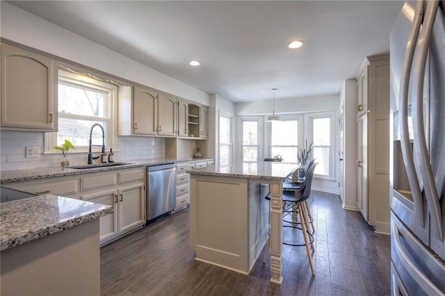 kitchen with a kitchen island, decorative light fixtures, sink, stainless steel appliances, and dark wood-type flooring