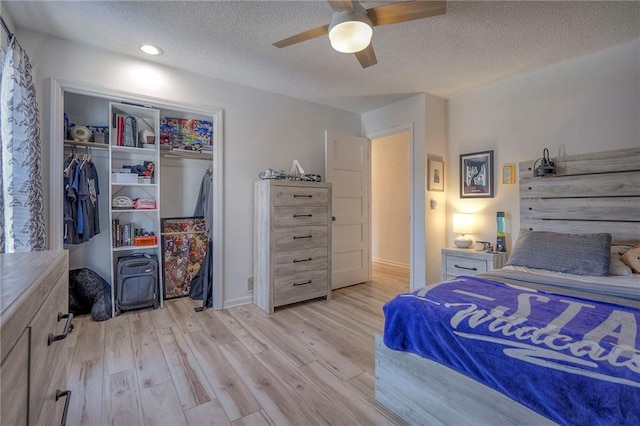 bedroom featuring ceiling fan, a closet, light hardwood / wood-style flooring, and a textured ceiling