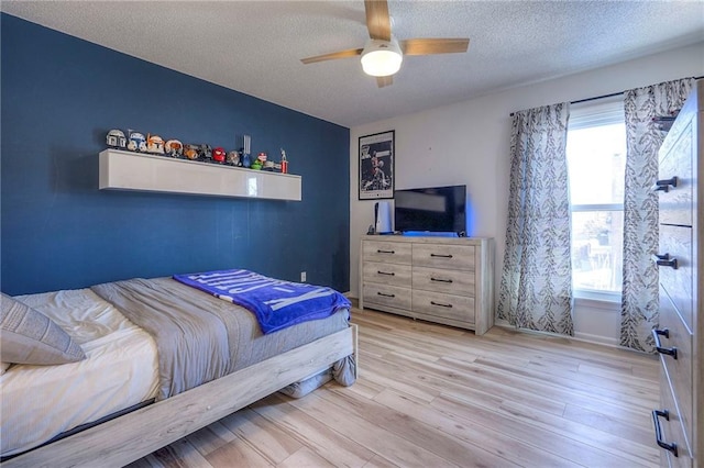 bedroom with ceiling fan, a textured ceiling, and light wood-type flooring