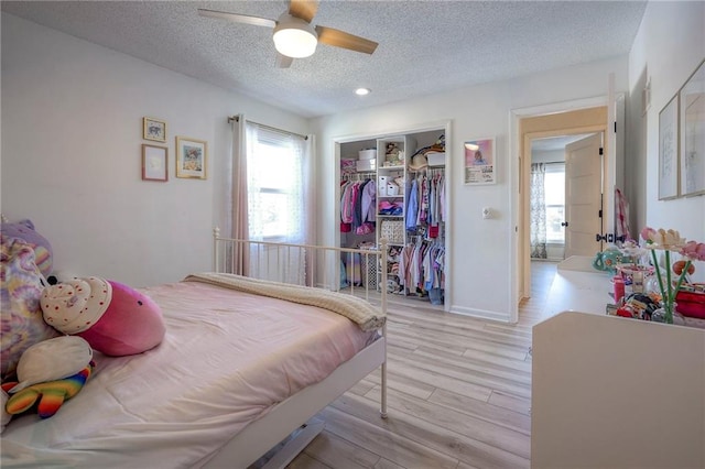 bedroom with multiple windows, a closet, a textured ceiling, and light wood-type flooring