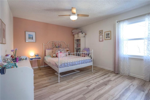 bedroom with ceiling fan, light hardwood / wood-style floors, and a textured ceiling