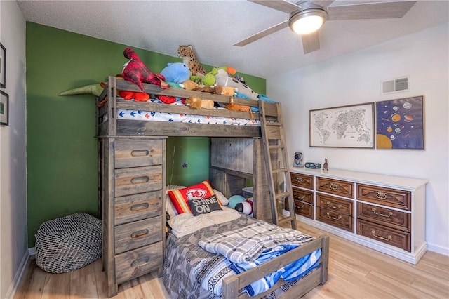 bedroom featuring wood-type flooring, ceiling fan, and a textured ceiling