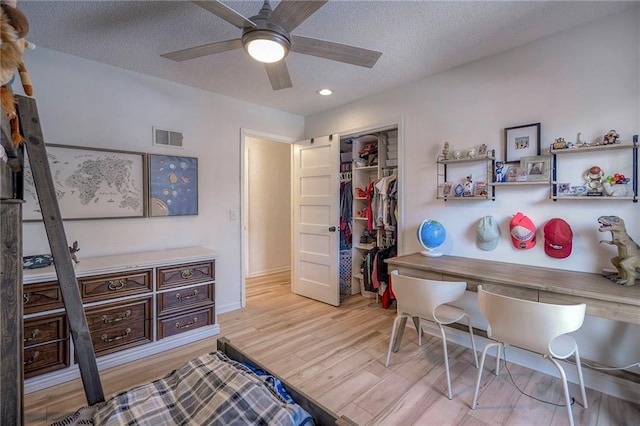 interior space featuring ceiling fan, light hardwood / wood-style flooring, a closet, and a textured ceiling