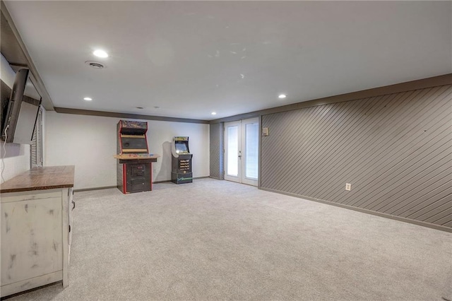 basement with french doors, light carpet, and wood walls