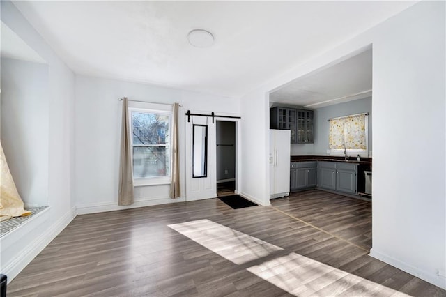 kitchen with dark hardwood / wood-style flooring, gray cabinetry, sink, a barn door, and white fridge with ice dispenser