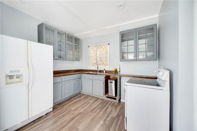 kitchen with gray cabinetry, sink, light hardwood / wood-style floors, and white appliances