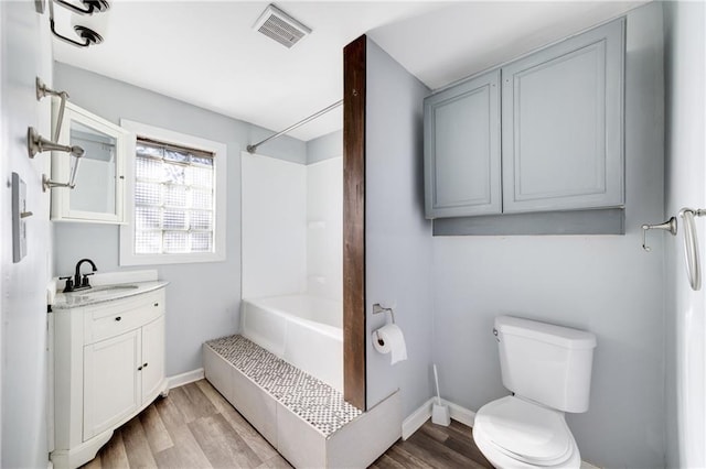 full bathroom with hardwood / wood-style floors, vanity, shower / bath combination, and toilet