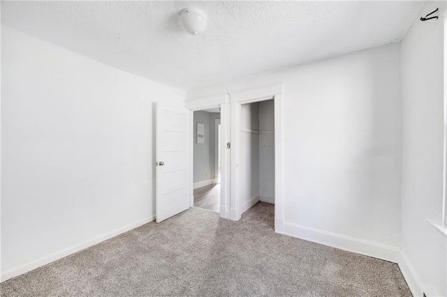 unfurnished bedroom with light carpet, a closet, and a textured ceiling