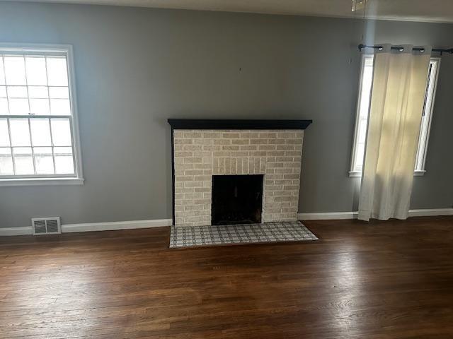 unfurnished living room with ceiling fan, dark wood-type flooring, and a brick fireplace