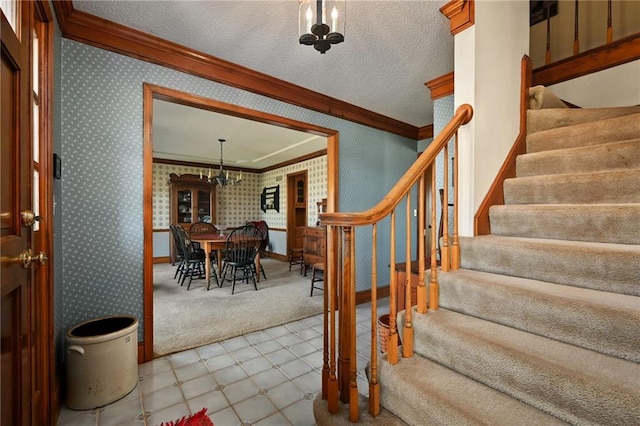 foyer with a textured ceiling, an inviting chandelier, and ornamental molding