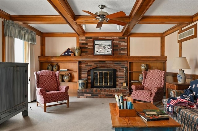 living room with ceiling fan, a brick fireplace, beamed ceiling, carpet floors, and a textured ceiling