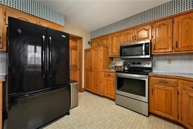 kitchen featuring decorative backsplash, stainless steel appliances, and a textured ceiling