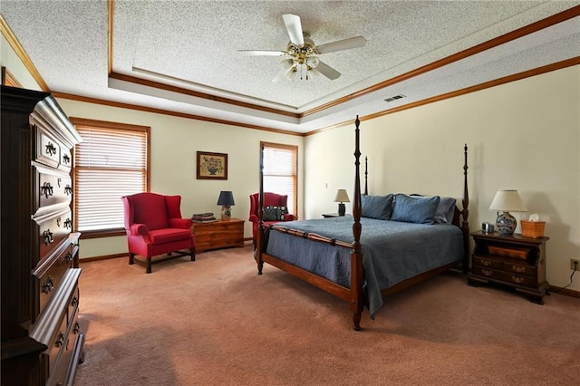 carpeted bedroom with a tray ceiling, ceiling fan, crown molding, and a textured ceiling