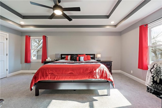 bedroom featuring light colored carpet, a tray ceiling, and multiple windows