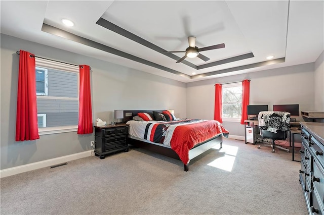 carpeted bedroom featuring a tray ceiling and ceiling fan