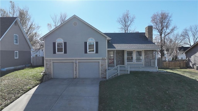 split level home with a garage, a front yard, and covered porch