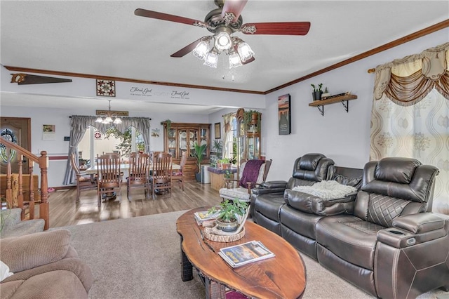living room featuring hardwood / wood-style floors, ceiling fan with notable chandelier, a healthy amount of sunlight, and crown molding
