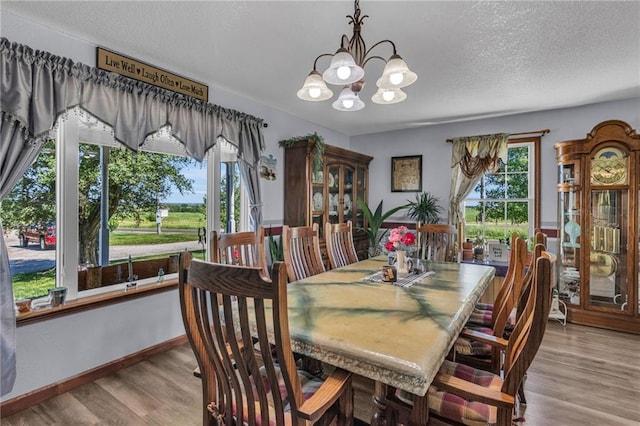 dining room featuring a textured ceiling, light hardwood / wood-style flooring, and a notable chandelier