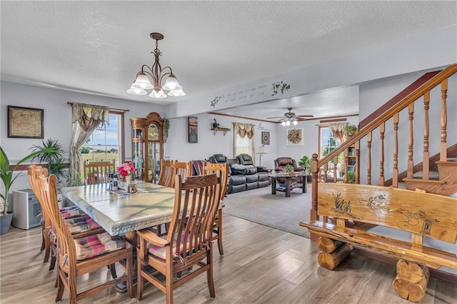 dining room featuring light wood-type flooring, a textured ceiling, and ceiling fan with notable chandelier