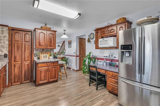 kitchen featuring light wood-type flooring, stainless steel fridge with ice dispenser, backsplash, and decorative light fixtures