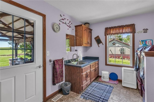 clothes washing area featuring cabinets, separate washer and dryer, and sink