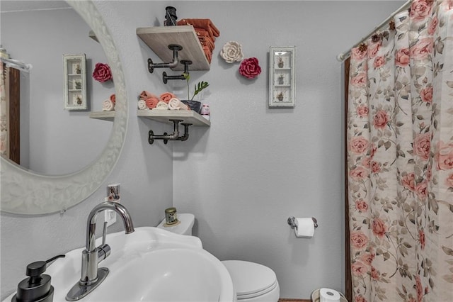 bathroom featuring a shower with curtain, toilet, and sink