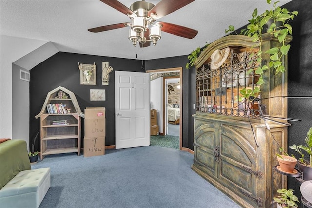 living area featuring carpet flooring, a textured ceiling, vaulted ceiling, and ceiling fan