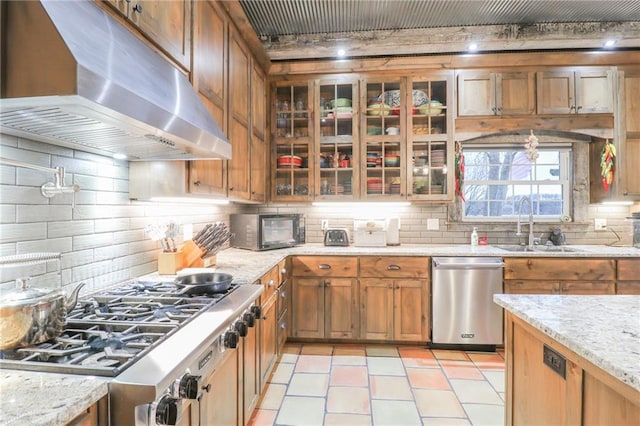 kitchen featuring decorative backsplash, appliances with stainless steel finishes, light stone counters, and sink