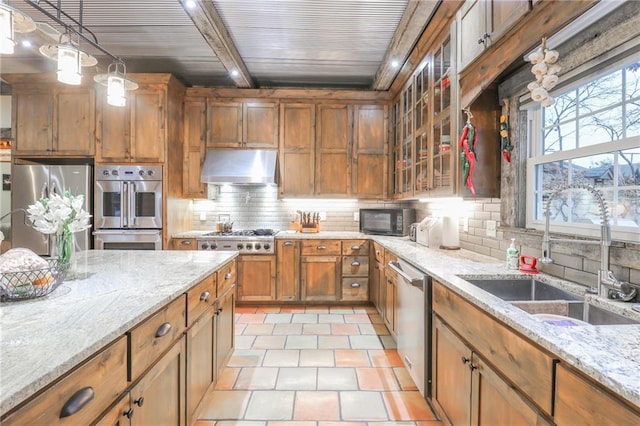 kitchen with hanging light fixtures, sink, light stone countertops, appliances with stainless steel finishes, and beam ceiling