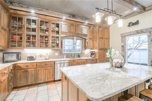 kitchen featuring dishwasher, hanging light fixtures, sink, a kitchen island, and a breakfast bar area