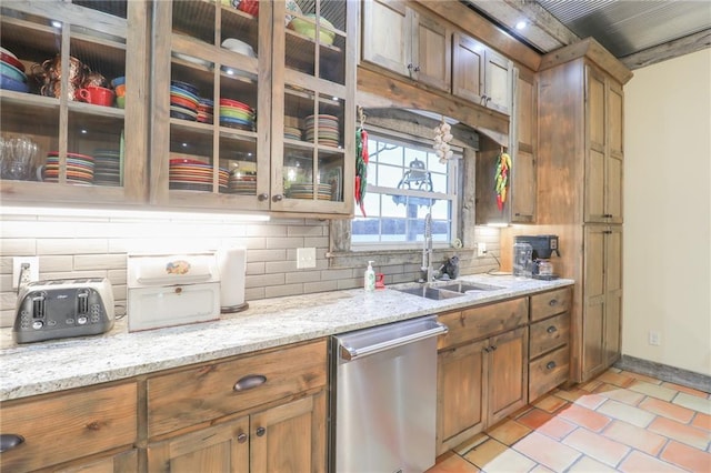 kitchen with sink, stainless steel dishwasher, tasteful backsplash, light tile patterned flooring, and light stone counters