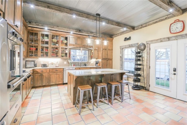 kitchen with beam ceiling, decorative light fixtures, a kitchen island, and a breakfast bar area