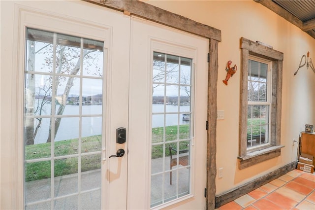 doorway to outside with tile patterned flooring, a water view, and a healthy amount of sunlight