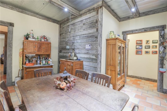 tiled dining area featuring beamed ceiling and wooden walls