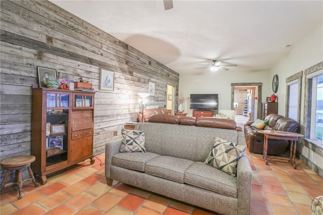 living room featuring ceiling fan and wooden walls