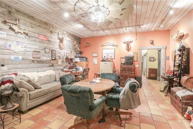 dining room featuring light tile patterned flooring, track lighting, wooden ceiling, and wood walls