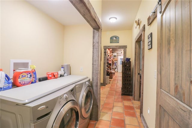 laundry room featuring a barn door, light tile patterned floors, and washing machine and clothes dryer