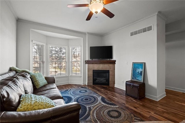 living room featuring dark hardwood / wood-style floors, ceiling fan, crown molding, and a fireplace