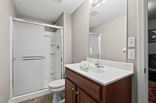 bathroom featuring tile patterned floors, vanity, a shower with shower door, and toilet