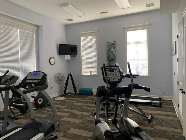 workout area featuring dark carpet and a wealth of natural light