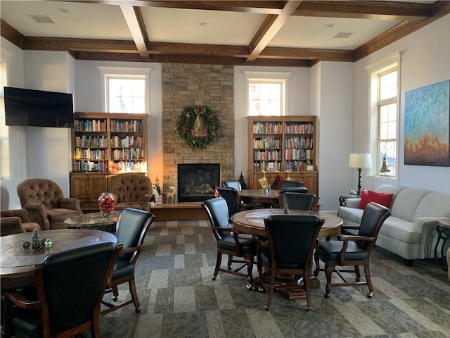 interior space with beam ceiling, a stone fireplace, and coffered ceiling