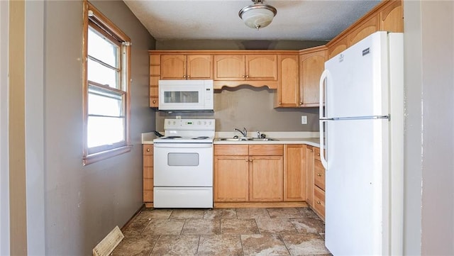 kitchen with light brown cabinets, white appliances, and sink