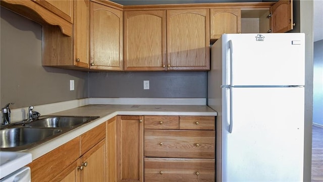 kitchen with hardwood / wood-style flooring, white refrigerator, and sink