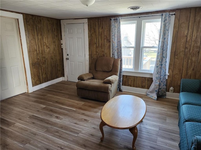 sitting room with hardwood / wood-style floors and wooden walls