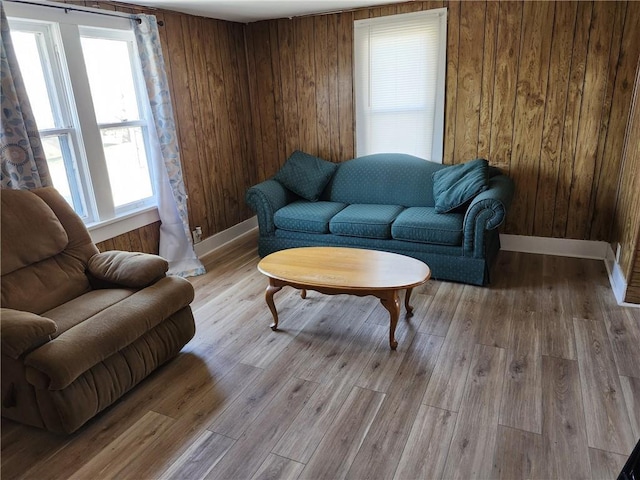 living room with wooden walls, light hardwood / wood-style flooring, and a healthy amount of sunlight