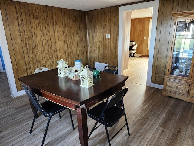 dining area with wood walls and hardwood / wood-style flooring