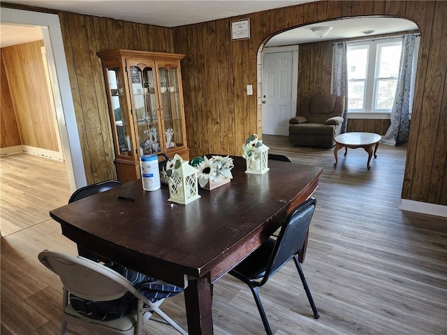 dining area with hardwood / wood-style floors and wood walls