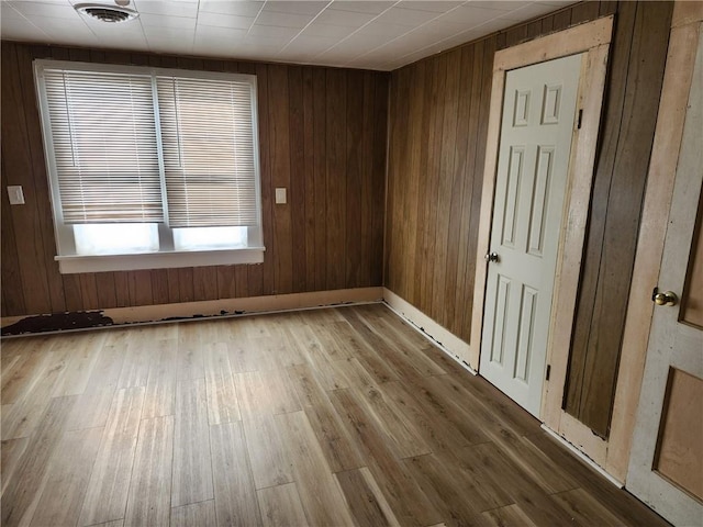 empty room featuring wooden walls and wood-type flooring