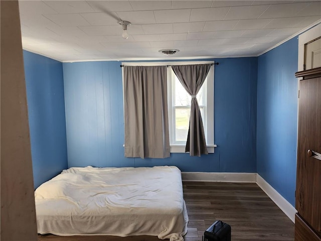 bedroom with dark hardwood / wood-style floors and ornamental molding